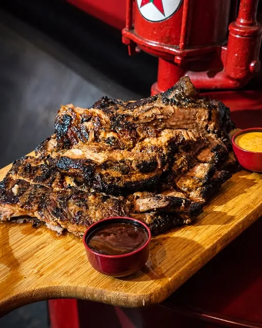 Su costillar a la parrilla sobre tabla, junto al surtidor Texaco del local